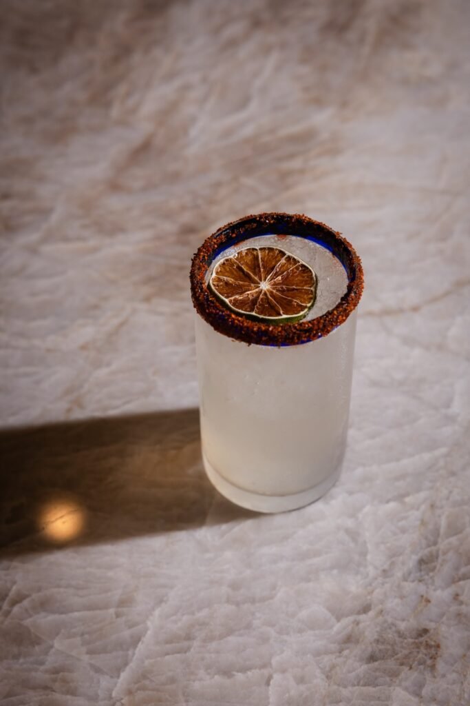 Ranch Water in a tall blue-rimmed glass with chile salt and a lime wheel