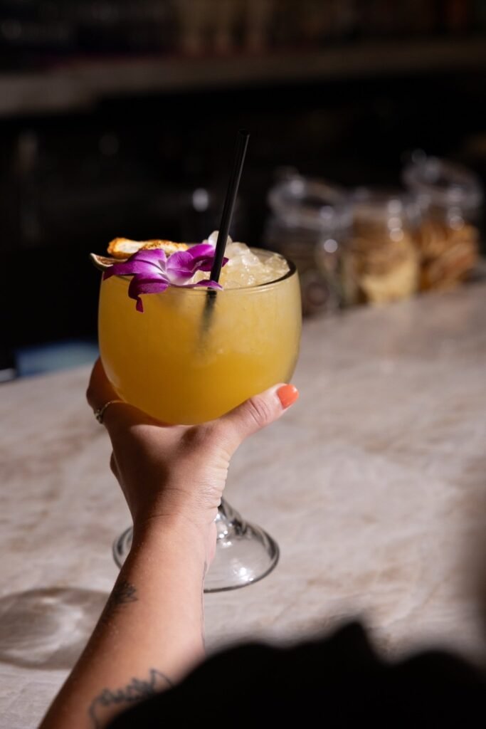 Skinny Margarita in a stemmed glass with citrus and an orchid garnish